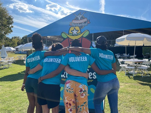 4 people standing in front of a big tent at a festival.